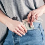 person in gray shirt and blue denim jeans holding blue denim jeans